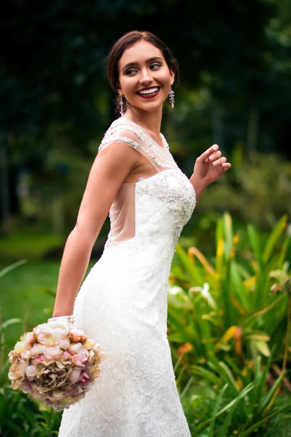 Novia sonriendo con su ramo en un jardín